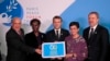 French President Emmanuel Macron, center, OECD secretary-general Angel Gurria, left, and U.N officers hold a placard as part of a move to promote gender equality at the Paris Peace Forum, Nov. 12, 2019. 