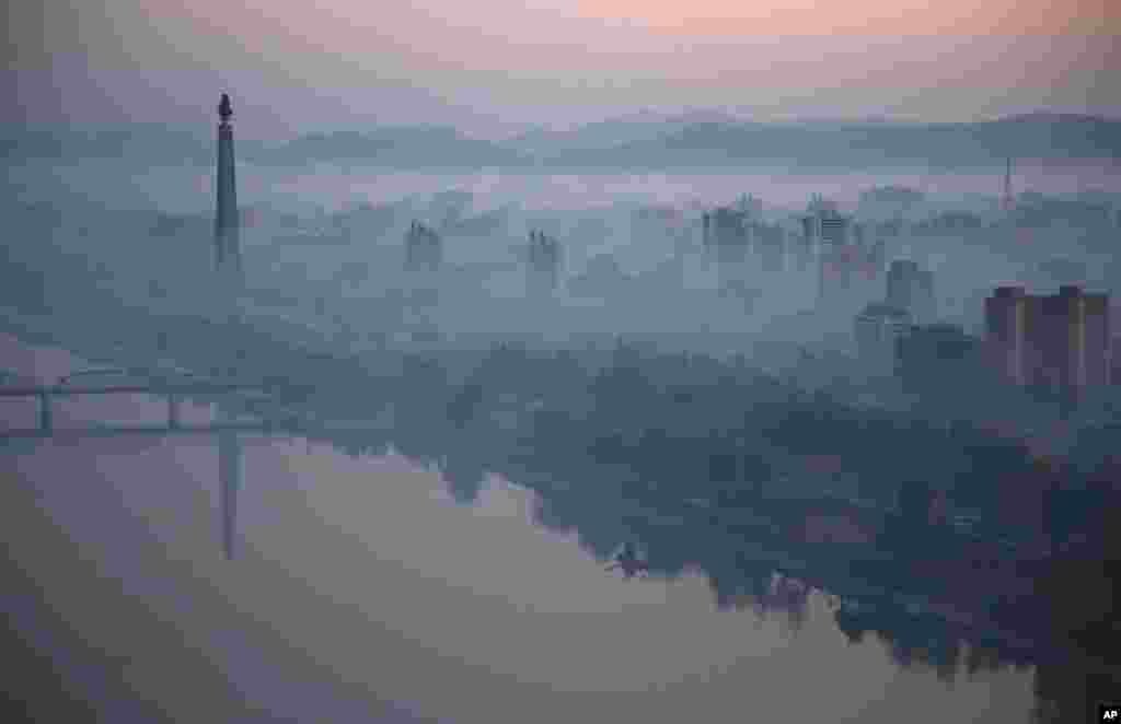 Dawn breaks over Pyongyang, North Korea, as buildings poke through the mist and the Juche Tower, left, stands by the Taedong riverbank.