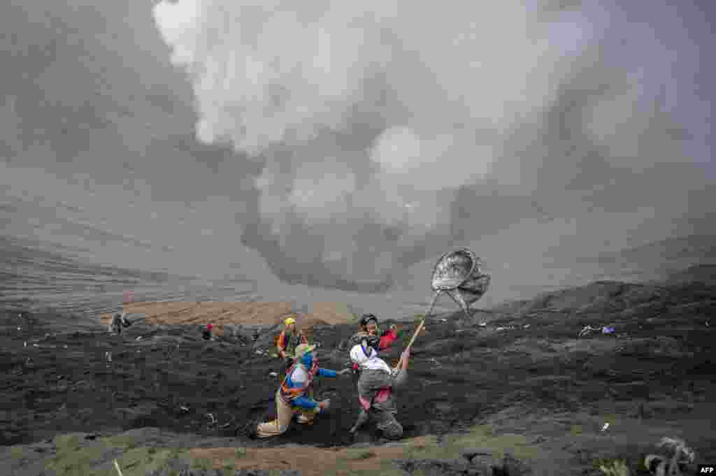 .Para penduduk desa menangkap sesajen uang logam yang dilemparkan oleh umat Hindhu suku Tengger selama perayaan festival Yadnya Kasada, di kawah Gunung Bromo di Probolinggo, Indonesia.&nbsp; Selama festival tahunan, suku Tengger mendaki Gunung Bromo, sebuah gunung berapi aktif, dan mencari berkah dari dewa utama Hyang Widi Wasa dengan memberikan sesajen yang terdiri dari beras, buah-buahan, binatang ternah, dan hasil bumi setempat. &nbsp;