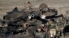 FILE - Russia-backed separatists walk after inspecting destroyed Ukrainian army tanks for functional weapons and ammunition near the village of Lohvynove, outside Debaltseve, Ukraine, Feb. 22, 2015.