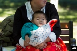 중국 베이징의 공원에서 한 여성이 자녀들을 안고 있다. (자료사진)