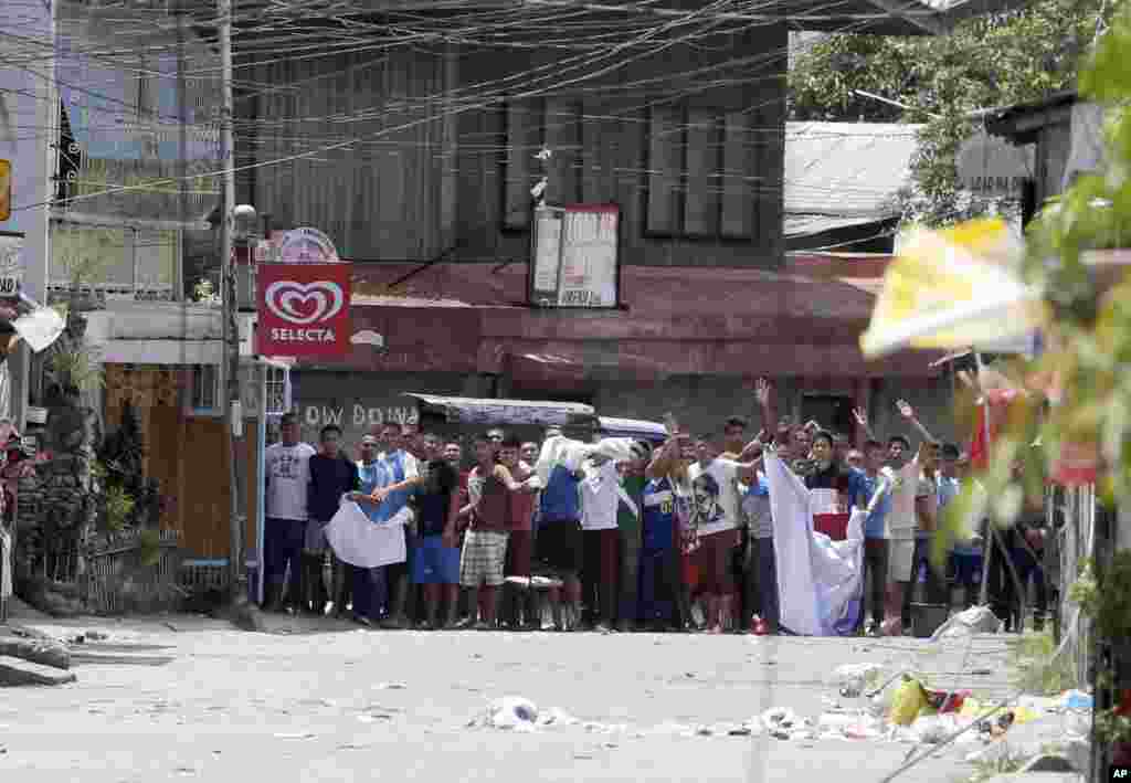 Warga yang diyakini sebagai sandera melambaikan kain putih sambil berteriak pada tentara untuk menghentikan operasi mereka dalam pertempuran melawan pemberontak Muslim di Zamboanga, Filipina (11/9).&nbsp;(AP/Bullit Marquez)
