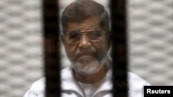 FILE - Ousted Egyptian President Mohamed Mursi is seen behind bars during his trial at a court in Cairo, May 8, 2014. 