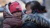 FILE - A Chinese woman cuddles her child in Beijing, China, March 6, 2014. China announced Thursday it was ending its long-standing one-child policy and will now allow all couples to have two children.