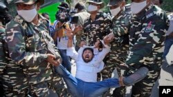 Paramilitary force soldiers detain an activist protesting against Sunday's killing of four farmers in Uttar Pradesh state after being run over by a car owned by India's junior home minister in New Delhi, India, Oct. 4, 2021. 