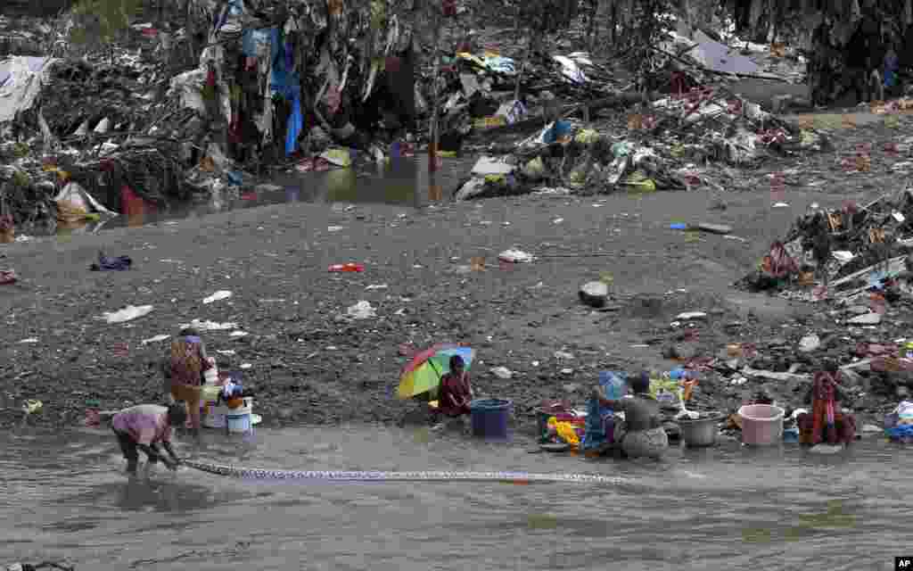 Residents wash clothes recovered from their flood damaged houses on the banks of the Adyar River in Chennai, India.