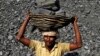 FILE - an Indian daily wage laborer carries a basket on his head filled with chunks of coal at a local coal depot on the outskirts of Cuttack, India, Nov. 13, 2014. 