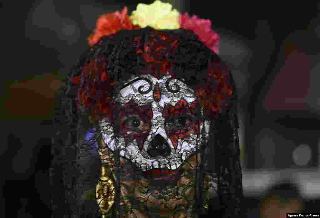 A transgender person looks on near offerings for victims of hate crimes on an alter, as part of Day of the Dead ceremonies, by civil organizations for the human rights of transgender people, in Mexico City, Nov. 2, 2021.