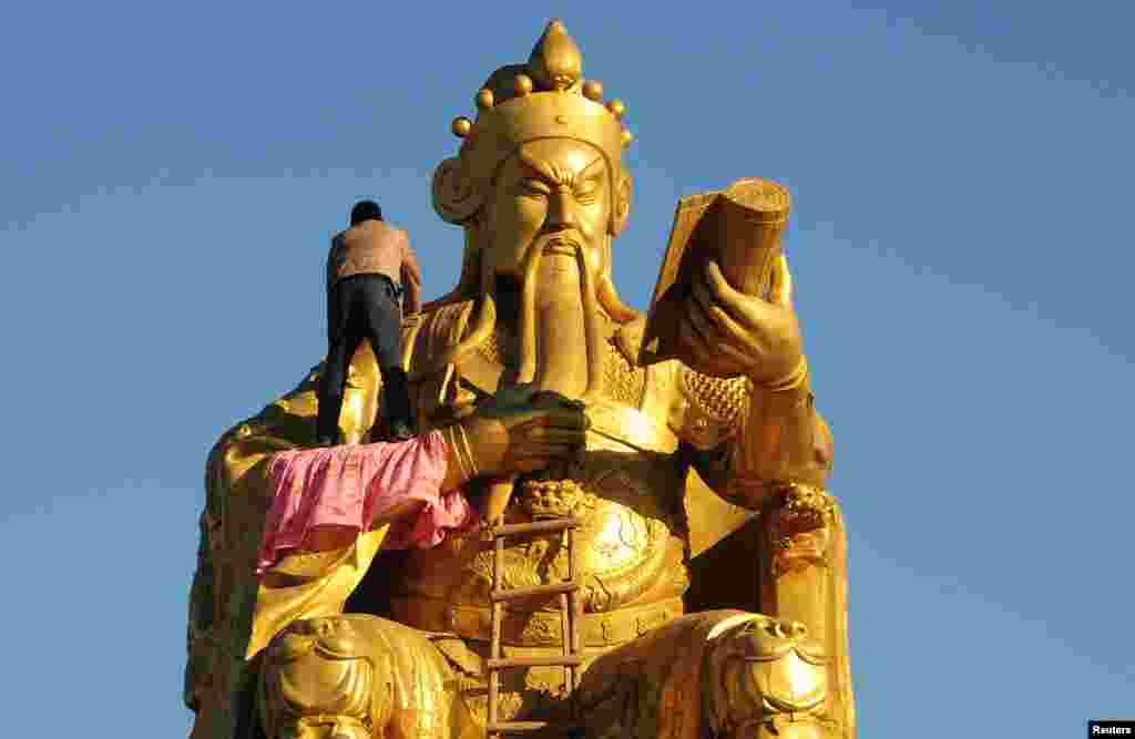 A worker paints a bronze statue of Guan Yu, a Chinese historical figure, in Nanyang, Henan province.