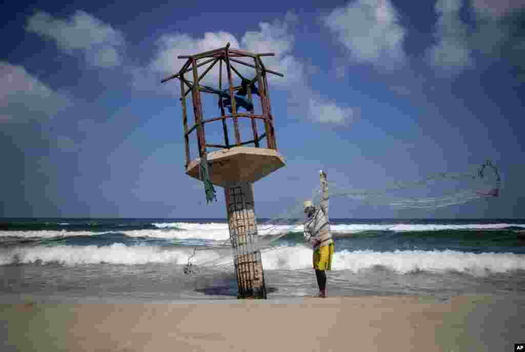 A Palestinian fisherman cleans up his fishing net after the Israeli decision to close Gaza's fishing zone, on the beach in Gaza City.