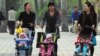 FILE - Women push babies in prams through a Beijing park during a public holiday, April 5, 2011.
