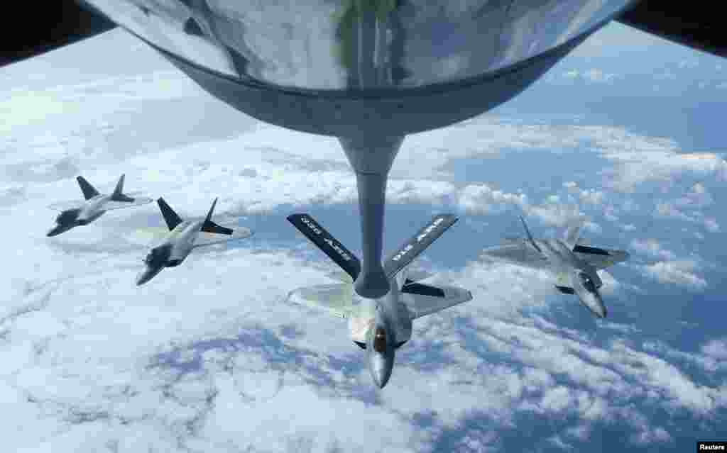 Empat pesawat jet tempur AS, F22 Raptors terbang dalam sebuah formasi setelah mengisi bahan bakar dengan Stratotanker KC-135R saat melakukan latihan militer &quot;RIMPAC&quot; di Honolulu, Hawaii.