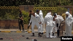 Forensic policemen inspect the site of a suicide bomb attack at a parade square in Sanaa, Yemen, May 21, 2012. 