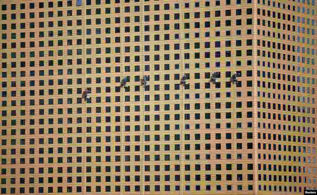 Workers clean windows of an office building in central Seoul, South Korea.