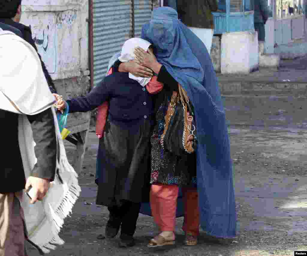 A woman and her daughter walk away after a blast near the Pakistani consulate in Jalalabad, Afghanistan. Afghan security forces exchanged fire with gunmen barricaded in a house near the Pakistan consulate in the eastern city of Jalalabad after a suicide bomber blew himself up, officials said.