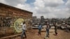 FILE - Children walk past graffiti depicting a representation of the coronavirus and warning people to sanitize to prevent its spread, in the Mathare slum of Nairobi, Kenya, April 22, 2020.