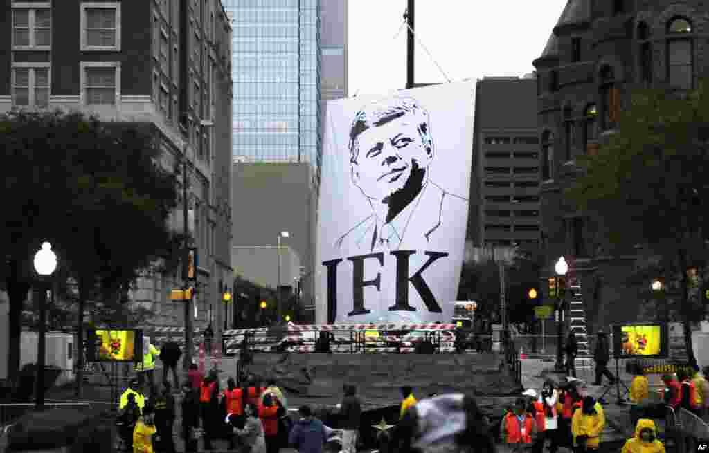 A banner of John F. Kennedy is lowered to the stage before a ceremony to mark the 50th anniversary of his assassination, near Dealey Plaza in Dallas, Texas, Nov. 22, 2013.