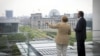 German Chancellor Angela Merkel and Greek Prime Minister Antonis Samaras (R) chat while standing on a balcony of the Chancellery before holding a meeting in Berlin, August 24, 2012.