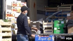 A worker unloads produce at a Paris market that has since been shuttered because of coronavirus-related health restrictions. (VOA/Lisa Bryant)