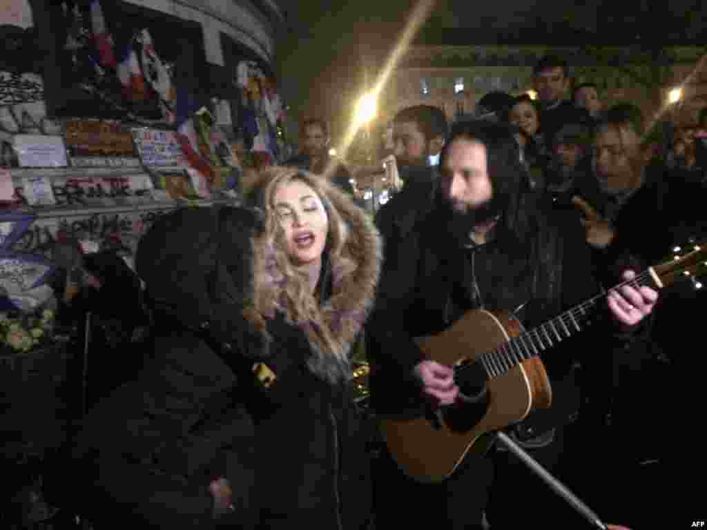 Singer Madonna (C) sings next to her guitarist Monte Pittman (C-R) and her son David Banda (L) at the place de la Republique in Paris at a makeshift memorial in tribute to victims of the Nov. 13 terror attacks in Paris.