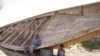 Des survivants assis près d’une pirogue similaire à une autre qui a fait naufrage, à Goma, RDC, 5 septembre 2006.