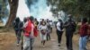 Demonstrators run from teargas fired by police at a protest against alleged corruption, including the theft of supplies for the fight against the coronavirus, at Uhuru Park in downtown Nairobi, Kenya, Aug. 21, 2020.