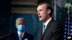 FILE - With his boss-to-be in the background, Jake Sullivan, then Joe Biden's pick to become national security adviser, speaks at The Queen theater, Nov. 24, 2020, in Wilmington, Del. 