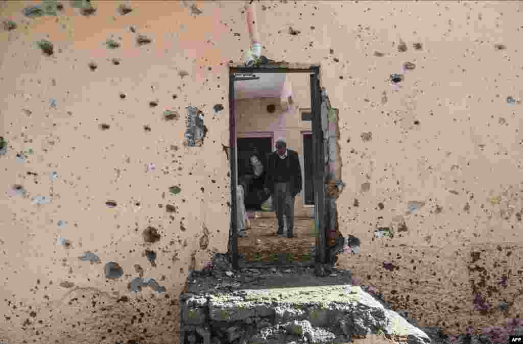 People walk inside their damaged house in the Sur district in Diyarbakir, Turkey. The district has been under military curfew for eight days. Turkey has been waging a relentless offensive against PKK strongholds in the southeast of the country and in northern Iraq following the collapse in July of a two-year truce with rebels.