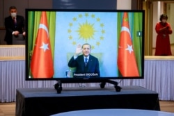 Turkey's President Recep Tayyip Erdogan waves from the video monitor as he participates in a video conference with European Commission President Ursula von der Leyen and European Council President Charles Michel in Brussels, March 19, 2021.