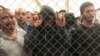FILE - In this July 12, 2019, photo, men stand in a U.S. Immigration and Border Enforcement detention center in McAllen, Texas.