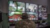FILE - A fighter with the Syrian Democratic Forces (SDF) monitors on surveillance screens prisoners accused of being affiliated with the Islamic State (IS) group, at a prison in the northeastern Syrian city of Hasakeh, Oct. 26, 2019. 