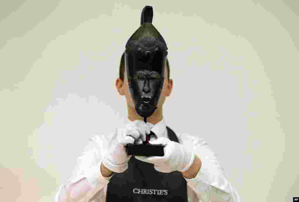 A Christie&#39;s employee holds &#39;The Mendes-France Baule Mask&#39; from Ivory Coast at Christies&#39;s auction rooms in London.
