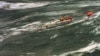 FILE - The injured crew of demasted Australian yacht "Stand Aside" await rescue by helicopter as they tow a life-raft in Bass Strait during the Sydney-to-Hobart ocean race, Dec. 27, 1998.