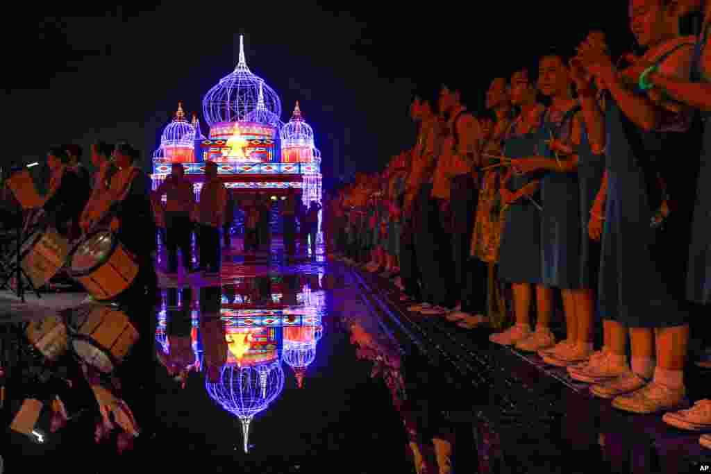 Students line up in front of an illuminated decoration symbolizing Russia during a light show in Kuala Lumpur, Malaysia.