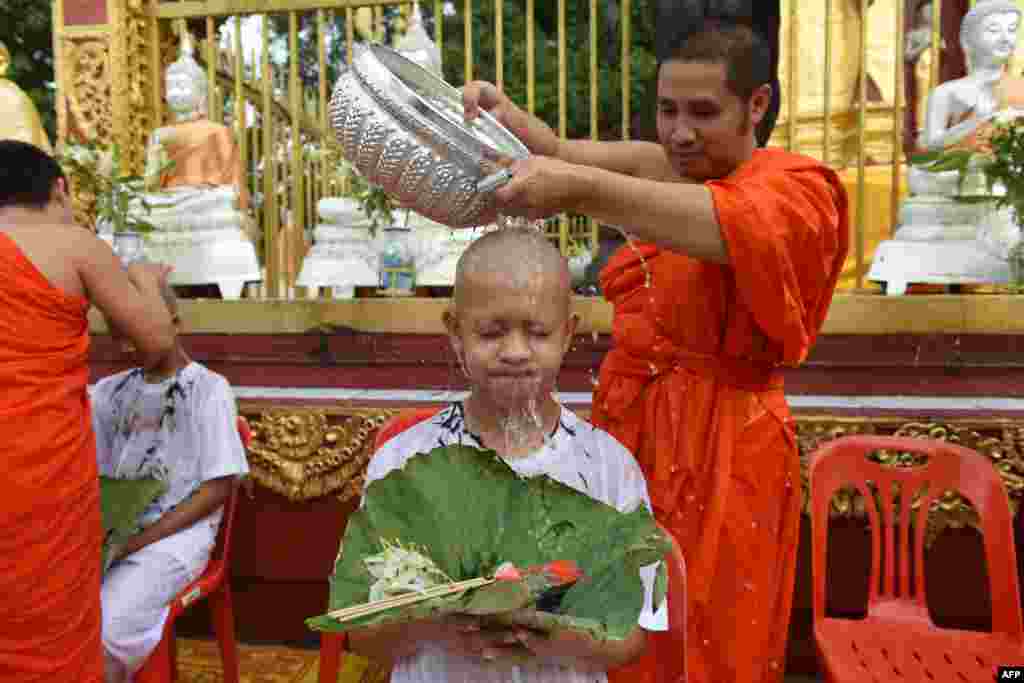 ព្រះសង្ឃ​​ពុទ្ធសាសនា​មួយ​អង្គ​ស្រោច​ទឹក​កុមារា​ជនជាតិ​ថៃ​នៃ​ក្រុម​បាល់​ទាត់​&laquo;Wild Boars&raquo; បន្ទាប់​ពី​ត្រូវ​បាន​កោរសក់​រួច​​នៅ​វត្ត Phra That Doi Wao ​ស្រុក​ Mae Sai ​ខេត្ត​ឈៀង​រ៉ៃ​។