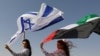 FILE - Israeli model May Tager, holding an Israeli flag, poses with Dubai-resident model Anastasia, holding an Emirati flag, during a photoshoot for FIX's Princess Collection in Dubai, UAE, Sept. 8, 2020.