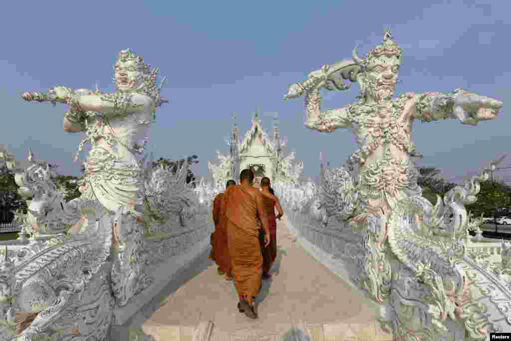 Buddhist monks take a tour at Wat Rong Khun, also know as the White Temple, designed by Thai visual artist Chalermchai Kositpipat in Chiang Rai Province, Thailand.