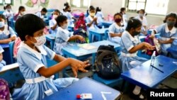 FILE - Students apply hand sanitiser while attending a class at the Viqarunnisa Noon School & College after the government has withdrawn restrictions on educational institutions following a decrease in the number of cases of COVID-19 in Dhaka, Bangladesh, Sept. 12, 2021. 