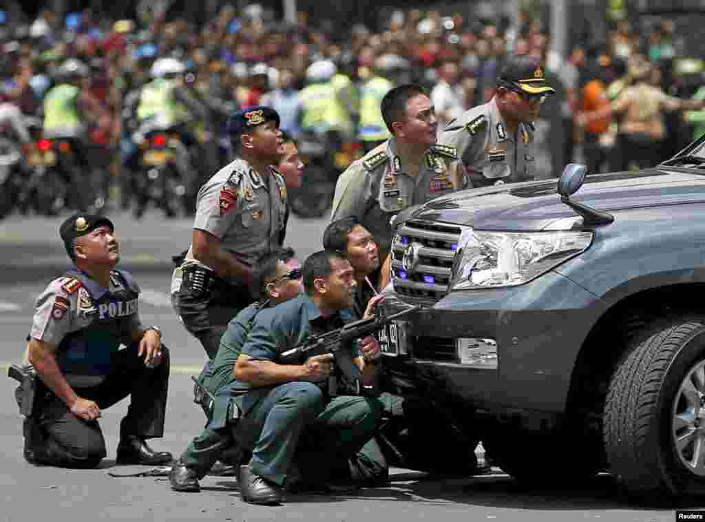 Police officers take a position behind a vehicle near the site of a blast in Jakarta, Indonesia. Several explosions went off and gunfire broke out in the center of the capital, leaving&nbsp;seven people dead, including all five attackers. The Islamic State group claimed responsibility for coordinated bomb and gun attack.