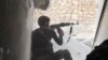 FILE - An Islamic State fighter aims his rifle in Kobani, Syria.