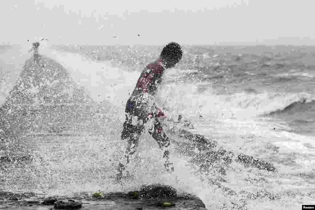 A boy searches for reusable plastic bottles while being pelted by waves brought by typhoon Koppu in Manila Bay. Powerful typhoon Koppu ploughed into the northeastern Philippines before dawn destroying homes and displacing 10,000 people and whipping up coastal surges four meters (12 feet) high, disaster agency officials said.