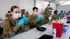 FILE - U.S. Army health specialists fill syringes with the Pfizer COVID-19 vaccine, in Miami, Florida, March 9, 2021.