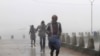 People run for shelter as heavy rain and wind gusts rip through the Bay of Bengal coast at Gopalpur, Orissa, about 285 kilometers (178 miles) north east of Visakhapatnam, India, Sunday, Oct. 12, 2014. 