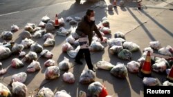 中国陕西西安新冠防疫封城后一名工作人员为居家隔离的小区居民准备食品供应。（2021年12月23日）