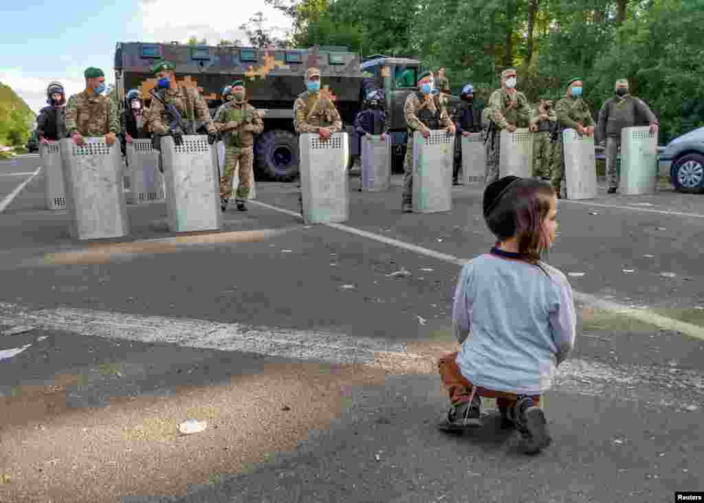 A Jewish pilgrim, who plans to enter Ukraine for a pilgrimage from Belarus, sits in front of Ukrainian service members near Novi Yarylovychi crossing point in Chernihiv Region, Ukraine Sept. 15, 2020.&nbsp;(Credit: BelaPAN)
