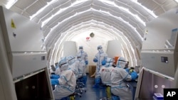Sejumlah pekerja sedang bekerja di laboratorium pengujian COVID-19 di Beijing, China, 23 Juni 2020. (Foto: Chen Zhonghao/Xinhua via AP)