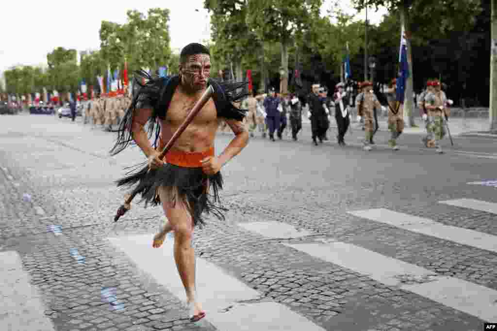Seorang pemuda etnis Maori berlari, sementara pasukan Selandia Baru berbaris di Champs Elysees di Paris pada gladi resik untuk parade perayaan Hari Bastille di Perancis.