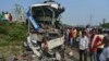 People stand near the wreckage of a bus that collided with a truck in Barabanki district, Uttar Pradesh state, India, Oct.7, 2021.