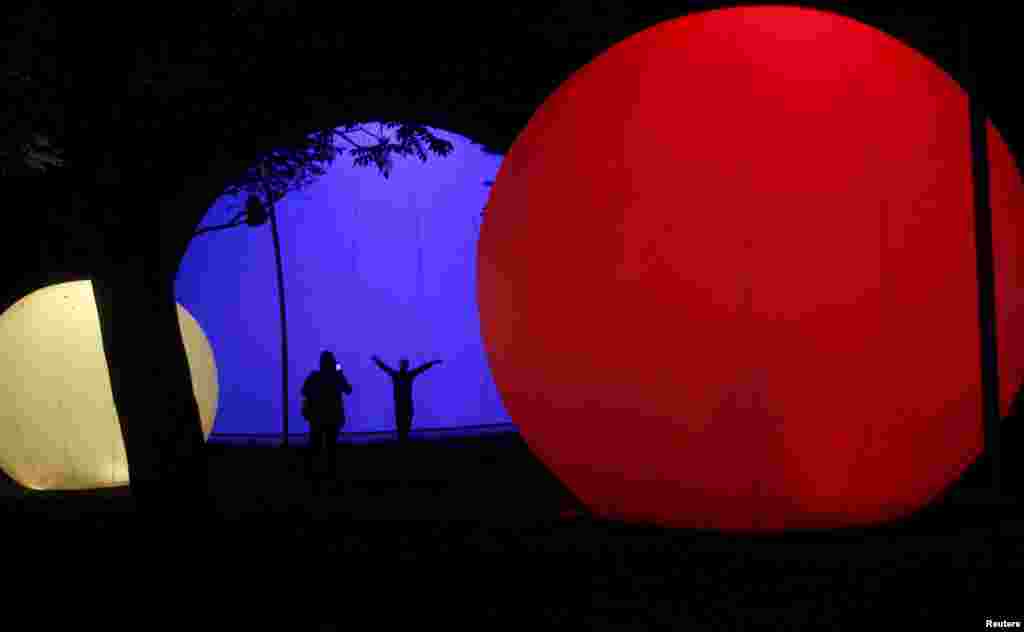 People take pictures with illuminated Christmas decorations on a street in Medellin, Colombia, Dec. 16, 2015.