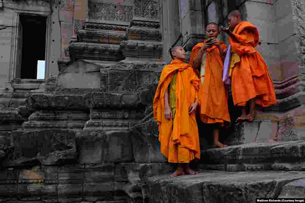 Novice Buddhist monks look at a mobile phone on the ruins of Prasat Hin Phimai, an ancient Khmer temple in Nakhon Ratchasima Province in northeast Thailand, Jan. 29, 2016.